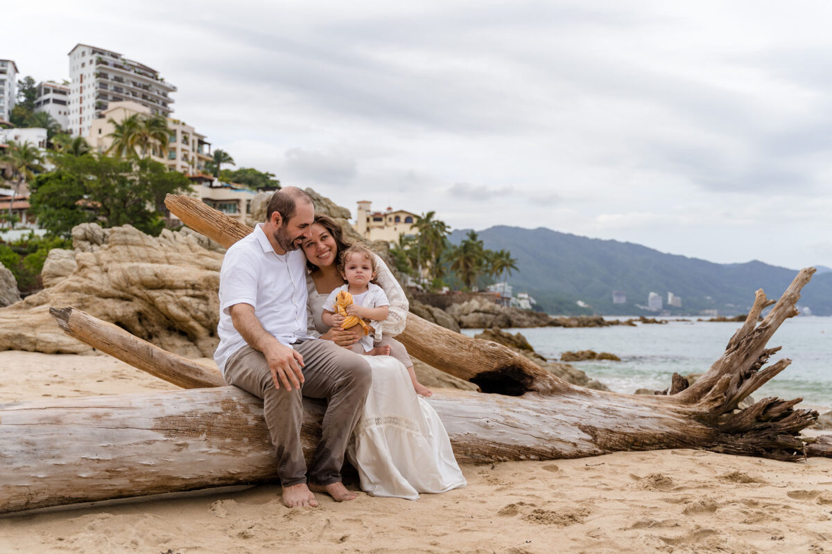 family on a trunk of wood on the beach