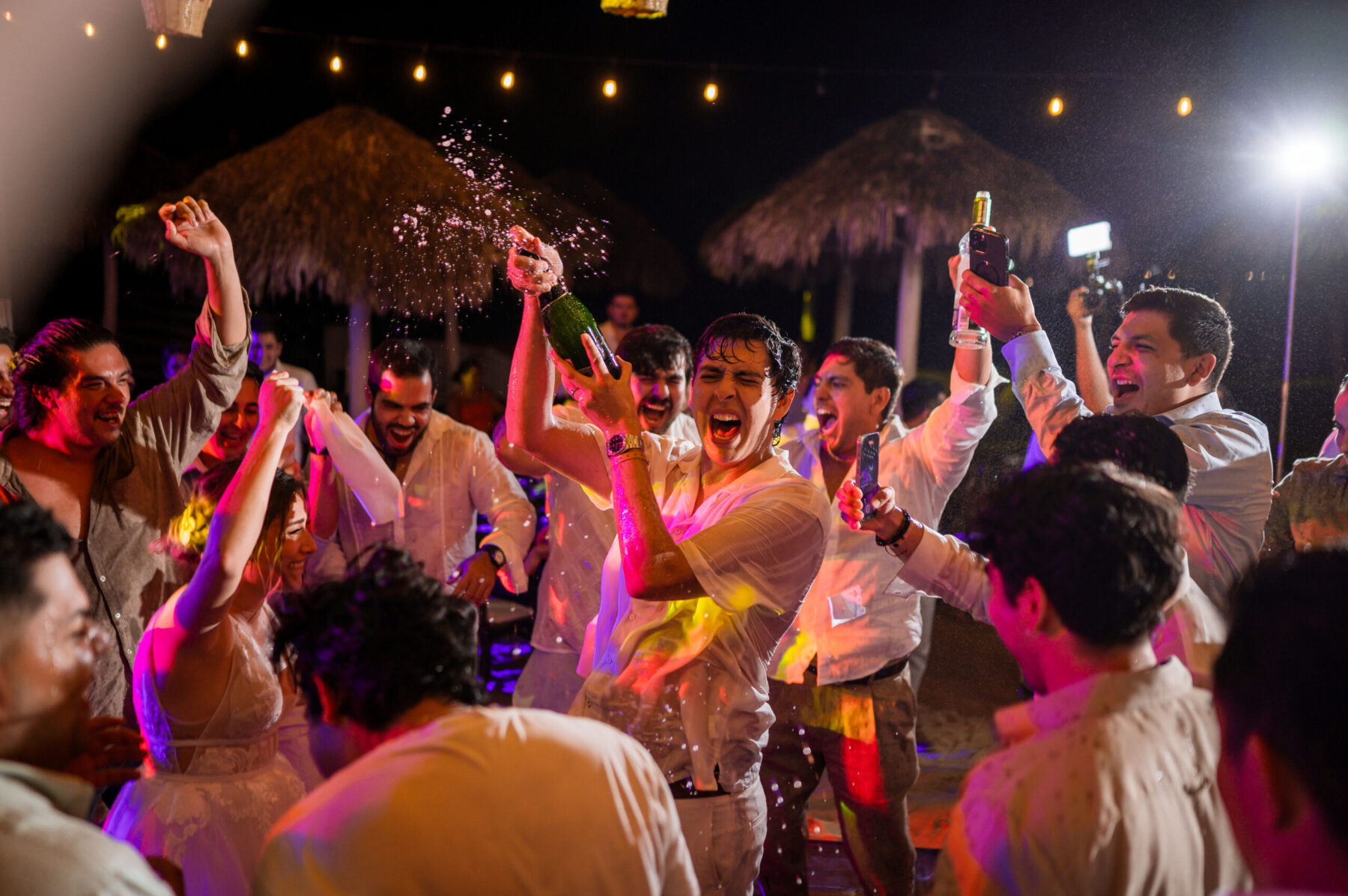 destination wedding mexico groom spraying champagne during party